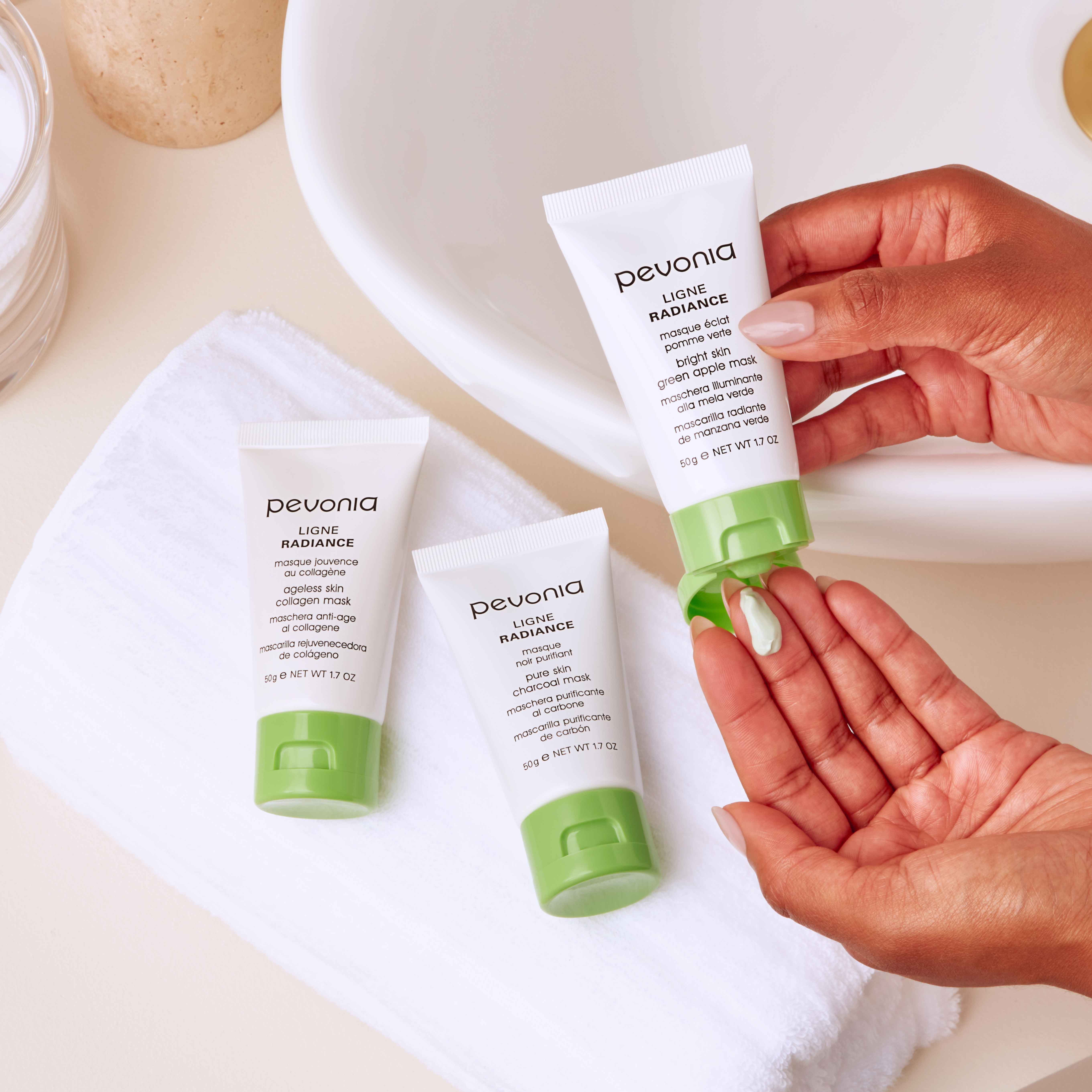 Woman with three Radiance Line masks, squeezing one out near the bathroom sink.