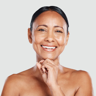 A woman standing in front of a tan background, smiling at the camera.
