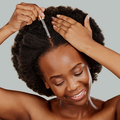 A woman applying Pevonia's Hair Energize Extra-Strength Overnight Serum.