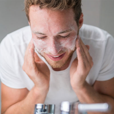 A man washing his face with Pevonia's Aqua-Gel Foaming Cleanser.