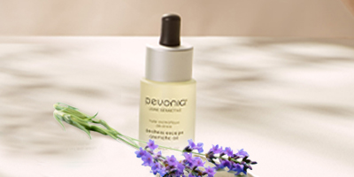Pevonia's De-Stress Escape Aromatic Oil with Lavender stems lying in front.