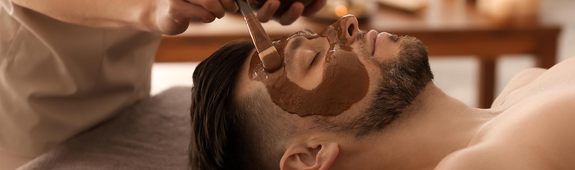 A man at a spa receiving a facial treatment with Pevonia's Chocolate Indulgence Mask.