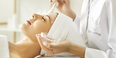 A woman receiving a facial treatment from a Pevonia Esthetician.